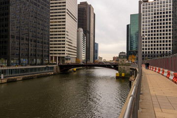a gorgeous autumn landscape along the Chicago River with cars driving over a bridge and office...