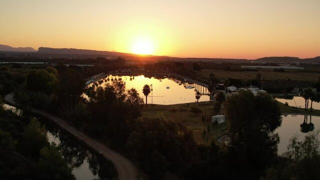 dawn in the wakepark. the drone rises up in the water the golden sunlight is beautifully reflected in the foreground a palm tree is growing no one has woken up yet. High quality 4k footage