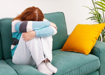 Depression and loneliness. Woman sitting alone on sofa in depressed mood