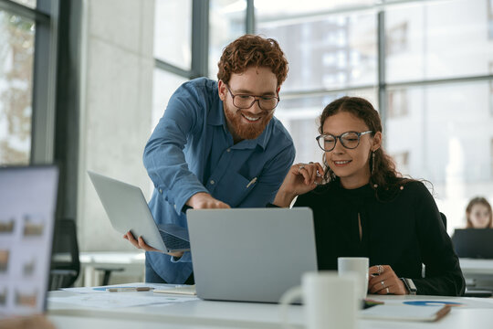 Two diverse business colleagues disscuss biz issue while use laptop in office background
