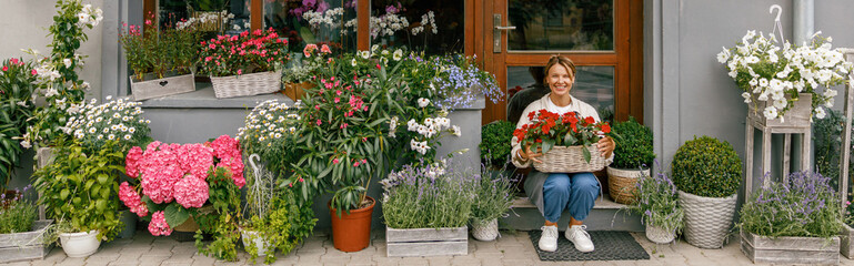 Fototapeta na wymiar Woman florist small business owner sitting in floral store and waiting for client with houseplants