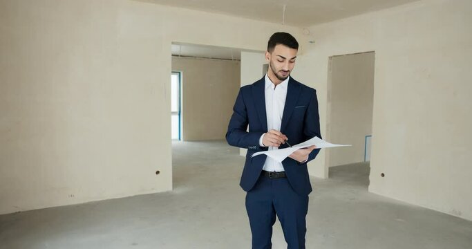 Sell man real estate manager agent showing new modern building to customers. Happy male is willing to sel a new building in countryside. Building without renovation .