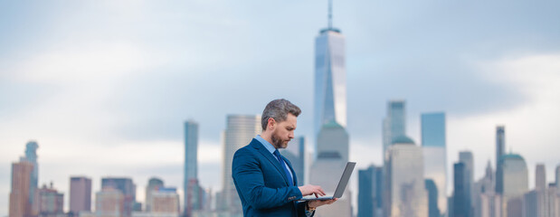 Businessman with laptop in New York City. Financial Manhattan. Office worker hold laptop against cityscape in NYC. Business man using laptop outdoor. Office work on laptop. Millennial freelancer. - obrazy, fototapety, plakaty