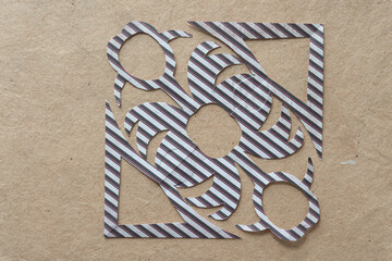 abstract folded and cut paper snowflake (made from scrapbooking square with stripes) on brown paper