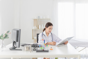 asian female doctor reading and order treatment process on patient chart, she sitting and smile in hospital