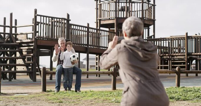 Happy, photograph and a grandparents at the park with their grandchild for a sports memory together. Family, phone or wave and a boy kid at the playground with his senior grandmother and grandfather