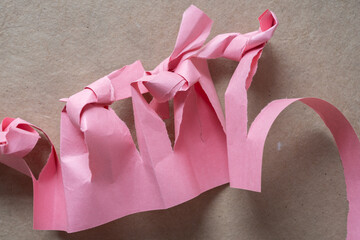 cut pink construction paper with knotted edges on brown paper