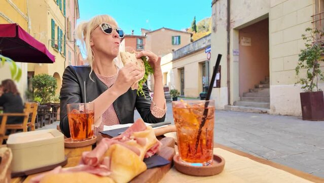 A tourist woman is enjoying a Piadina Romagnola in the heart of Brisighella, a historic Italian village. Downtown restaurant of Brisighella, a historic village nestled in Italy's Emilia-Romagna region