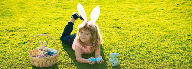 Easter kids boy in bunny ears hunting easter eggs outdoor. Cute child in rabbit costume with bunny...