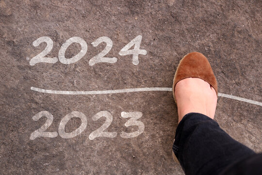 Woman leg moves from 2023 to 2024. happy new year 2024. lets start 2020. Woman walks on asphalt road from the end of 2023 to 2024. 