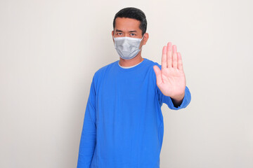A man wearing medical mask doing stop hand sign