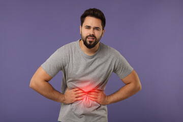 Man suffering from stomach pain on purple background
