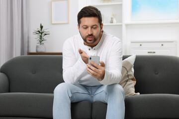 Man blowing kiss during video chat via smartphone at home. Long-distance relationship