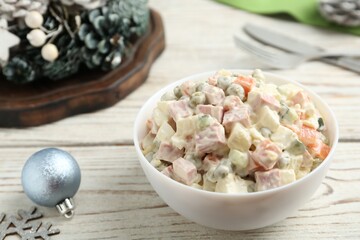 Traditional russian salad Olivier served on white wooden table