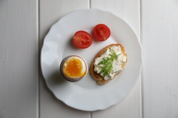 Breakfast with soft boiled egg on white wooden table, top view