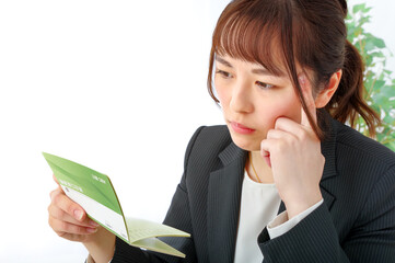 真剣な表情で通帳を見つめる若い女性