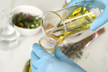 Scientist developing cosmetic oil at white table, closeup - obrazy, fototapety, plakaty