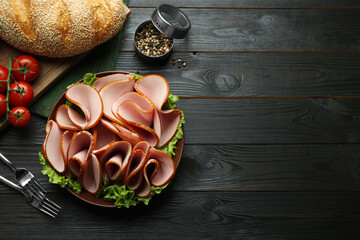 Slices of delicious boiled sausage and other products on dark wooden table, flat lay. Space for text