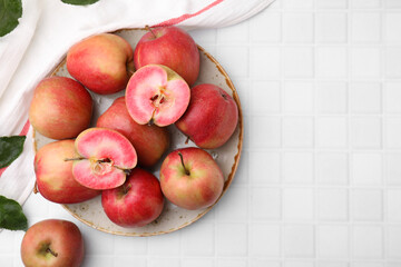 Tasty apples with red pulp and leaves on white tiled table, flat lay. Space for text