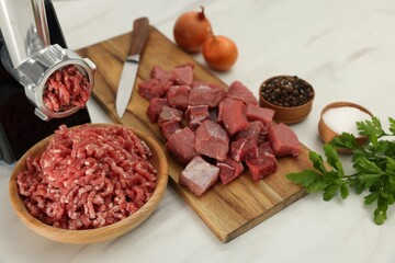 Electric meat grinder with beef and products on white marble table, above view