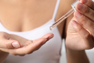 Woman applying cosmetic serum onto her finger, closeup