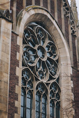Obraz premium Old openwork round window with stained glass on facade of the building. Baroque and Gothic architecture. Church of St. Olga and Elizabeth. Lviv, Ukraine.