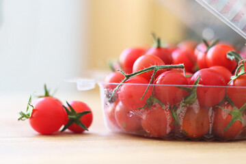 composicao com tomates cereja maduros. a maioria dentro de recipiente plástico sob luz natural...