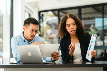 Asian business man and African American woman engaging in business discussion, possibly about merger or joint venture. two companies become one, one of companies often survives while other disappears