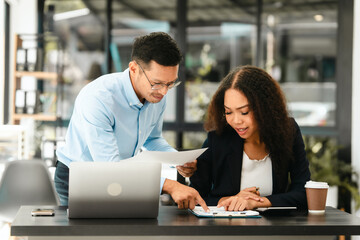 Asian business man and African American woman engaging in business discussion, possibly about merger or joint venture. two companies become one, one of companies often survives while other disappears