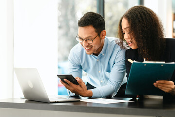 Asian business man and African American woman engaging in business discussion, possibly about merger or joint venture. two companies become one, one of companies often survives while other disappears