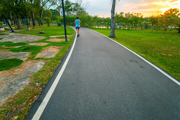 Asphalt road park on running walk way with green meadow grass sunset light