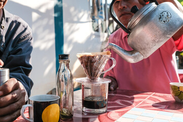 Man hand drrip brewing local coffee by paper filtered on table morning outdoor