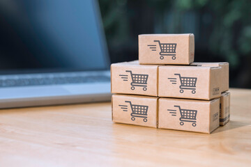 Paper cartons or parcel with shopping cart logo on laptop keyboard for online shopping or ecommerce and delivery service concept. Shopping service online and offer home delivery via the internet.