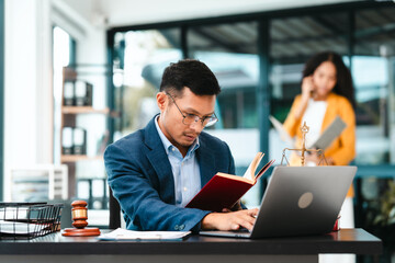 Attractive Asian businessman and an African American businesswoman, both in formal suits, intently review a contract paper together.