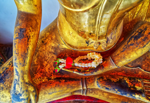 Close-up small garland on an ancient golden Buddha's hand in a temple, Landscape image.