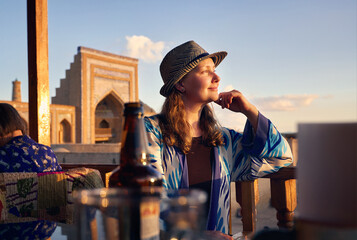 Tourist woman in ethnic dress near Madrassah in Ichan Kala of Khiva