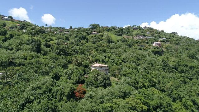 Drone Shot Around A Forested Hill With Houses Under A Suny Sky