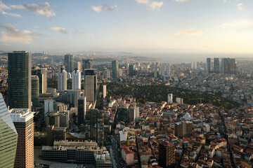 View from the window of a high-rise building to a modern city with skyscrapers, parks and sea coast.