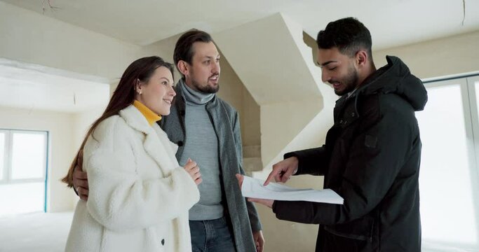 The developer selling the house discusses development plans, interior design with interested potential customers. A young couple watches and listens to a real estate agent asking questions.