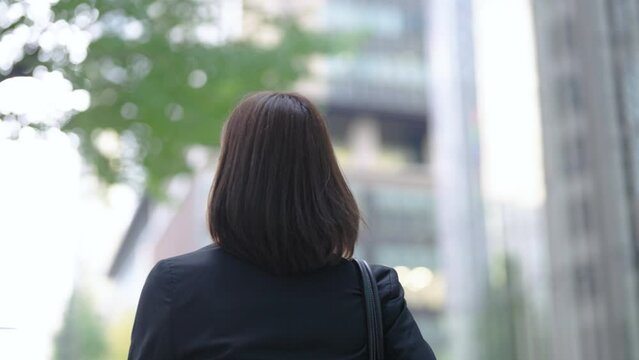 ビジネス街を歩くスーツ姿の女性の後ろ姿