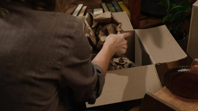 Removal concept. Person unpacks moving box of dishes.