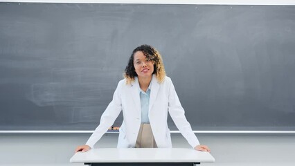 Female teacher teaching in front of the blackboard in the classroom.