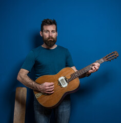 Obraz premium Young man playing guitar with blue background