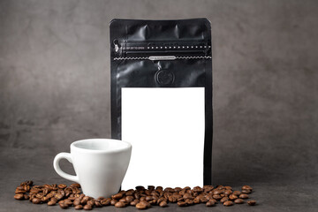 Black coffee foil packaging bag and coffee cup with blank white label on stone table