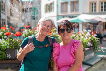 Portrait of happy senior female couple on vacation looking at camera smiling, two mature women enjoying vacation and freedom in sunshine