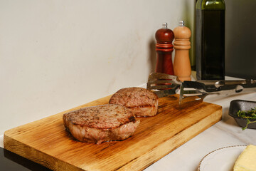 Two pieces of beef steak rest on wooden cutting board