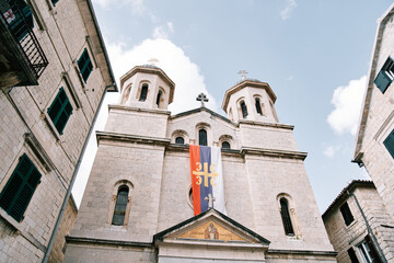 Fototapeta na wymiar Flag of the Serbian Orthodox Church on the facade of the Church of St. Nicholas in Kotor. Montenegro