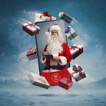 Santa Claus in a smartphone screen and Christmas gifts
