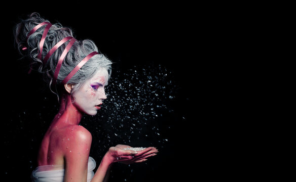 Beautiful model woman with creative makeup and white snow on black background