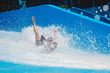 Young man surfing on a wave simulator at a water amusement park